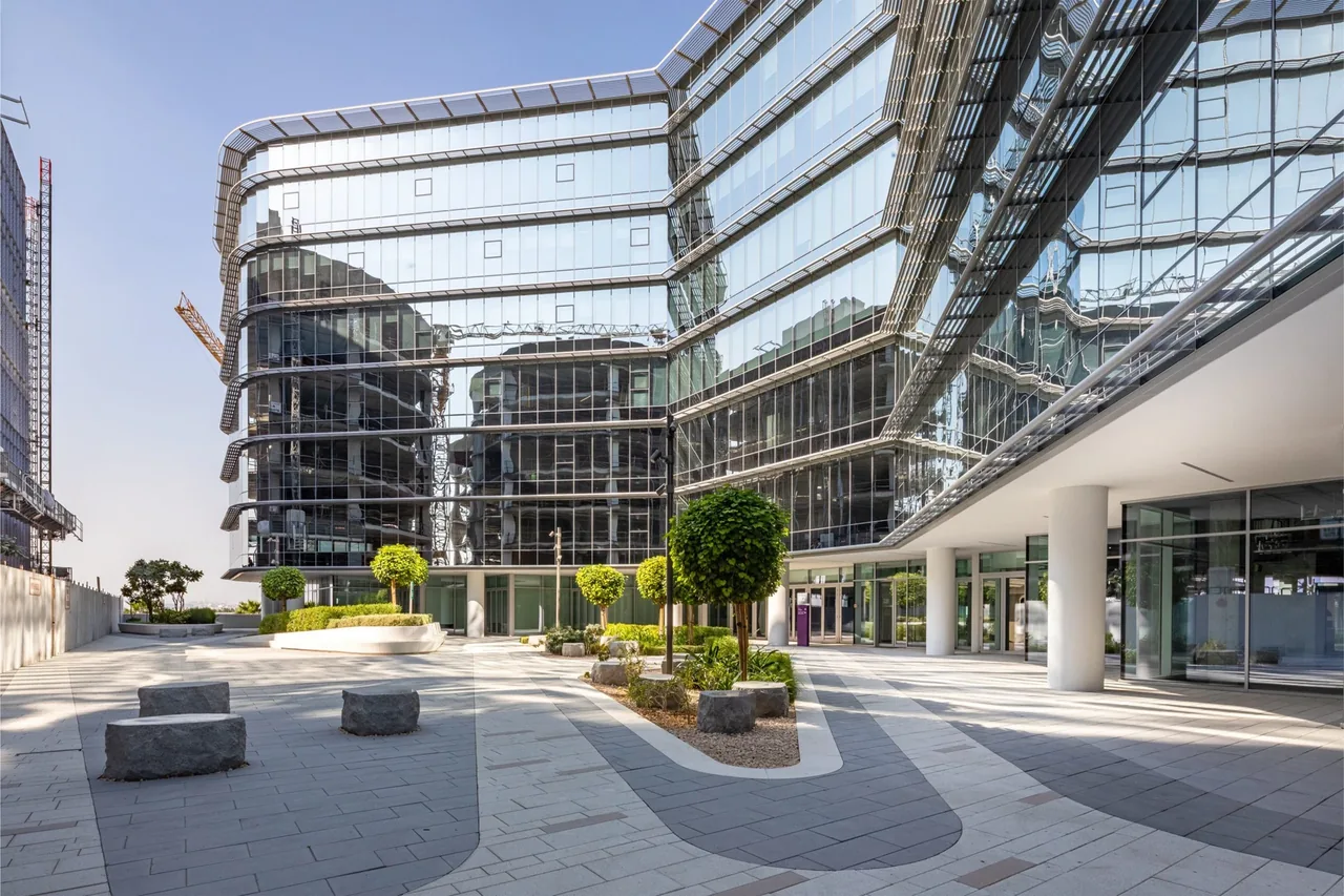Modern glass office building with landscaped plaza in Dubai